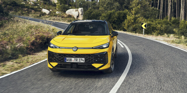 Ein gelber VW T-Roc fährt über eine Landstraße im Wald.