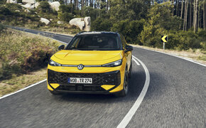 Ein gelber VW T-Roc fährt über eine Landstraße im Wald.