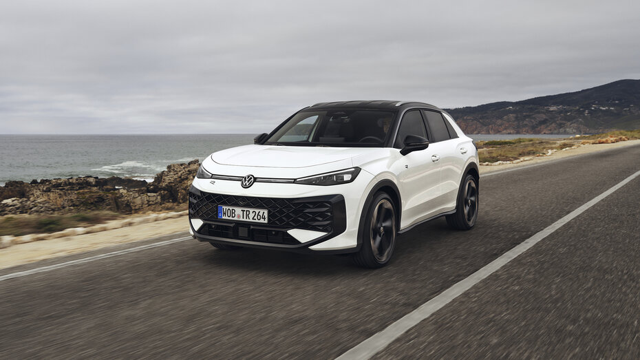 Ein weißer VW T-Roc fährt über eine Küstenstraße.