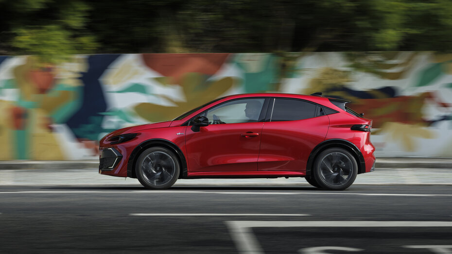 Ein roter Renault Clio fährt an einer Wand mit Graffiti vorbei.