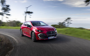 Ein roter Renault Clio fährt um die Kurve.