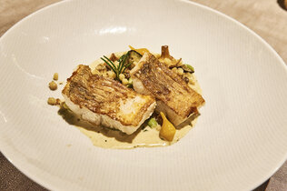 Ein Teller mit auf der Hautseite gebratenen Fischfilets.