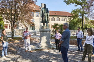Vor dem Museum ist im Kurpark ein Denkmal von Kaiser Franz Joseph aufgestellt. Parkbesucher betrachten es.