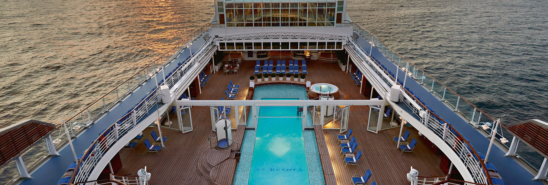 Zu sehen ist eine Ansicht des Decks der MS Europa von oben mit Blick auf das Pool bei Fahrt auf hoher See.