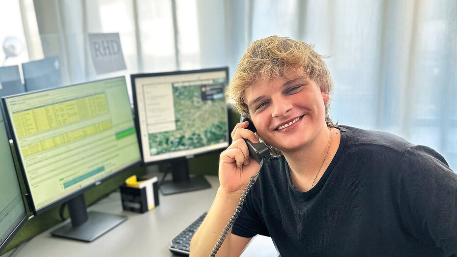 Junger ÖAMTC Mitarbeiter, er telefoniert. Seine Haare sind blond und er grinst.