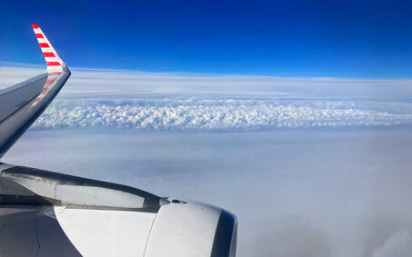 Blick auf den Himmel vom Flugzeug aus. Man sieht leicht die Tragfläche.