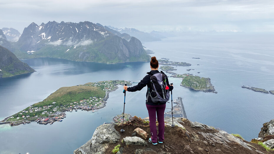 Panorama von einem See oder Meer mit Inseln. Im Vordergrund steht eine Frau mit Nordic Walking Stöcken.