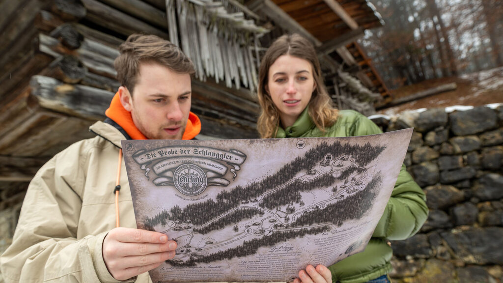 Ein Mann und eine Frau blicken auf eine Art Schatzkarte, die sie vor sich in den Händen halten.