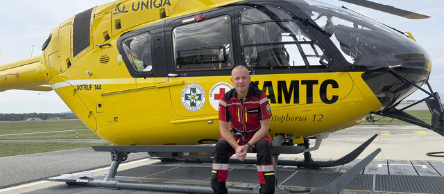 Flugretter Markus Amon sitzt in seiner Uniform vor einem Christophorus Helikopter.
