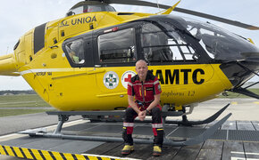 Flugretter Markus Amon sitzt in seiner Uniform vor einem Christophorus Helikopter.
