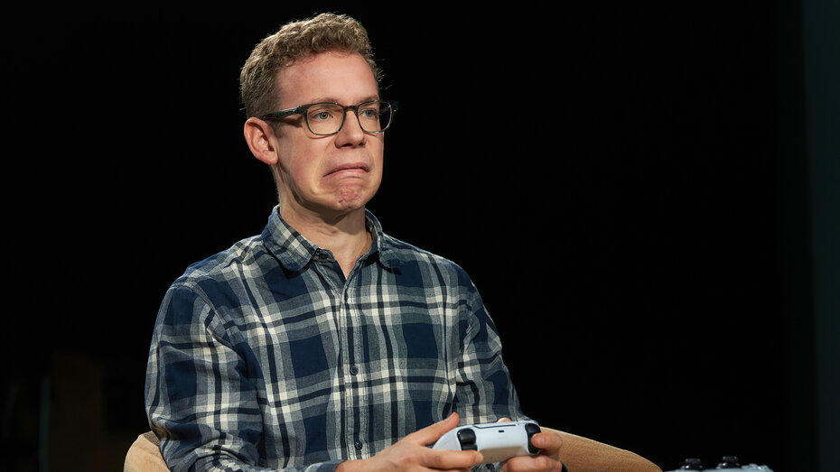 Redakteur Jakob Stantejsky sitzt mit verzogenem Gesicht in einem braunen Sessel und spielt mit einem PS5 Controller.