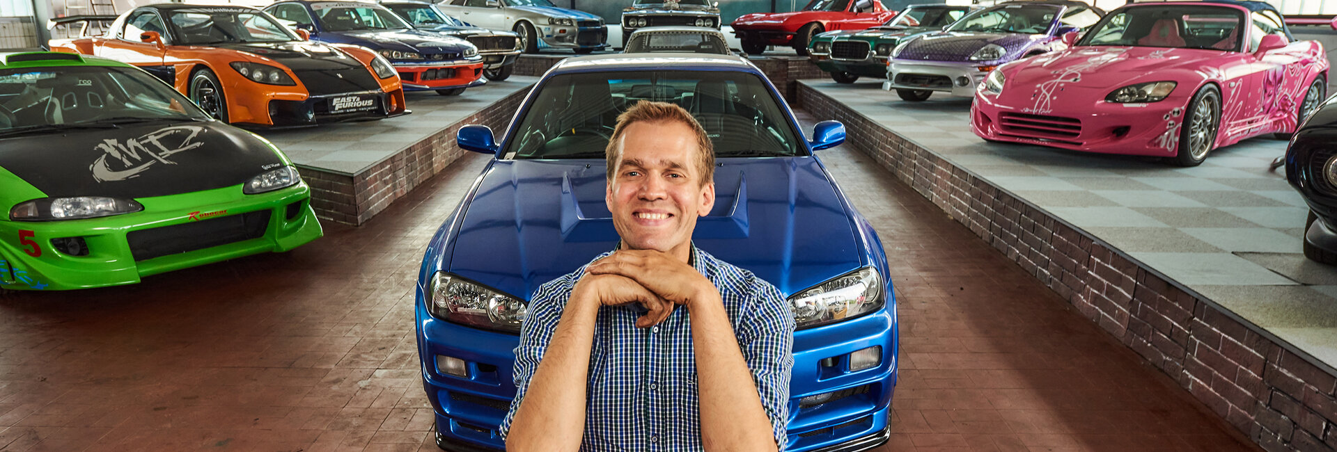 Martin Hahn sitzt vor Filmautos von "Fast an Furious".