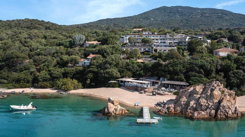 Die Hotelansicht ist vom Meer auf die kleine Bucht mit Sandstrand. Das Hotel ist in den Hang gebaut.
