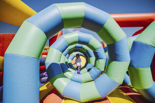 Eine Spirale in einer Hüpfburg, in der Mitte steht ein Kind.