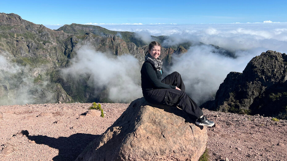 Redakteurin Verena Schauer auf einem Stein in Madeira. Hinter ihr ein Blick auf die Berge.