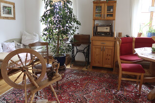 Wohnzimmer im Auszeithof mit Spindel, altem Radio und Esstisch.