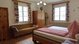 Gästezimmer im Auszeithof mit Bett, Kästen und Bank.