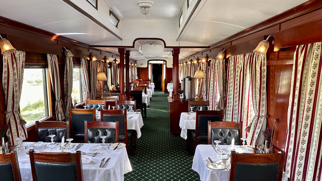 Schön gedeckte Tische mit weißen Tischtüchern im Speisewagen.