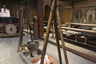 Eine Feuerstelle und ein langer Holztisch im Langhaus der Nordmänner.
