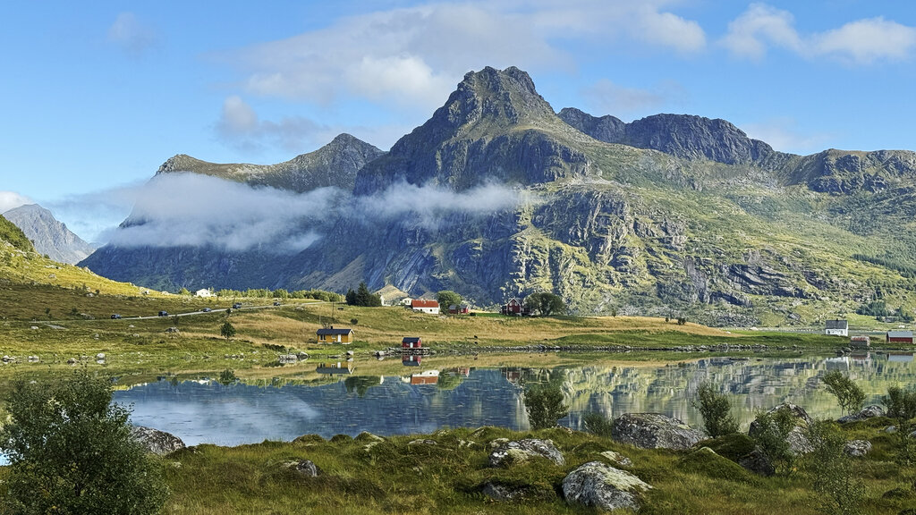 Spektakuläre Landschaft mit eine paar Häusern einem kleinen See und den Bergen.