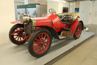 Ein rotes offenes Auto mit hölzernen Speichenrädern.