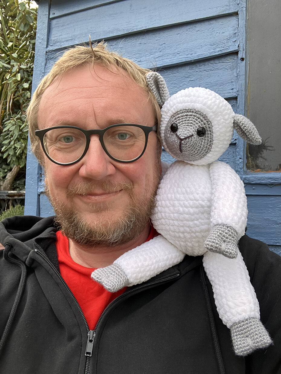 Foto zeigt Christoph Löger, den Autor des Artikels, mit einem gehäkelten Stoff-Schaf auf seiner Schulter.