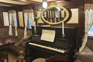 Museum: Ein Lounge am Schiffe mit Klavier und einer Sitzecke.