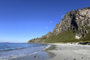 Küstenlandschaft mit Bergen und weißem Sandstrand.