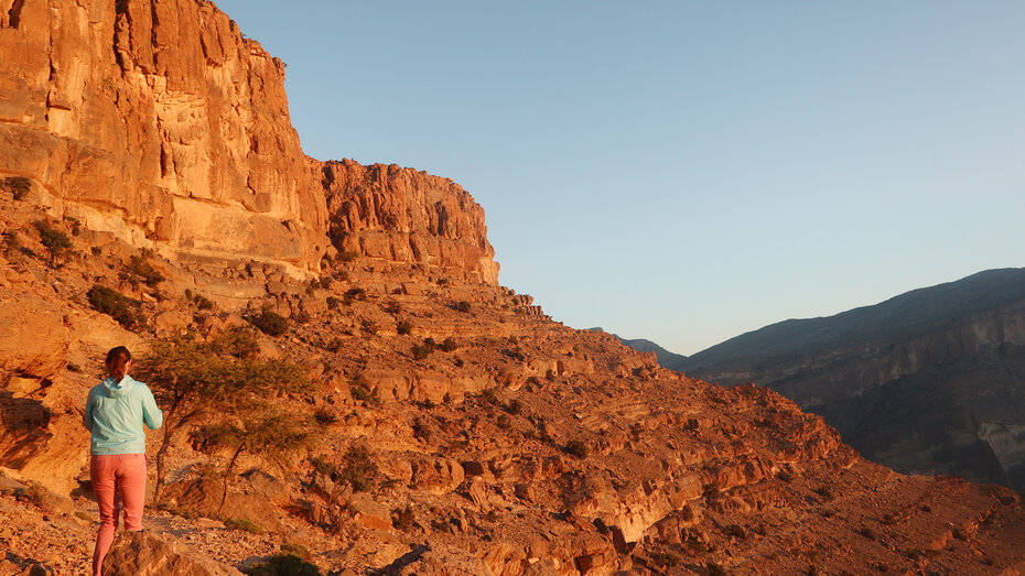 Eine Frau geht bei Sonnenuntergang den Felsen entlang für ein Foto.