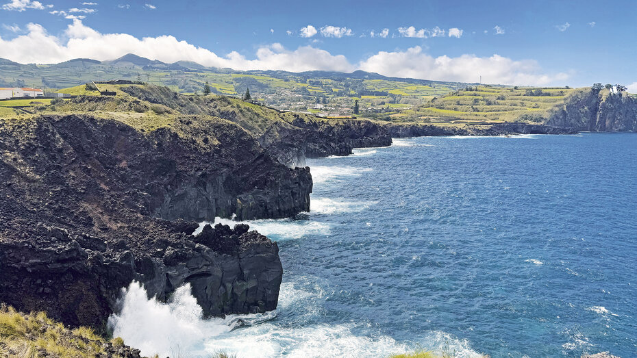 Die traumhafte grüne Küstenlandschaft mit schwarzen Lavafelsen und Klippen.