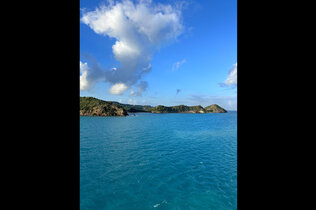 Blick vom Meer auf eine Küstenlandschaft bei strahlendem Wetter mit blauem Himmel.