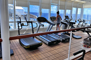 Man sieht den Fitness-Raum der MS Europa mit Blick auf das Wasser.