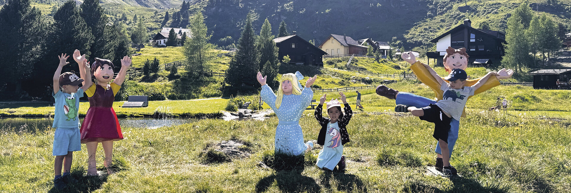 Drei Kinder stehen mit den Figuren von Heidi auf der Alm: Clara, Heidi und Peter.