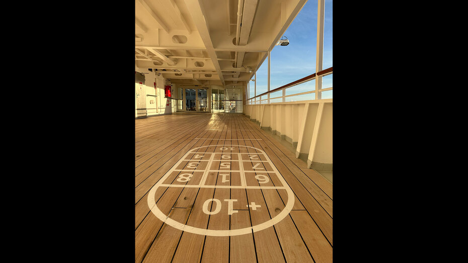 Detailbild des Bretterbodens an Deck der MS Europa im Licht zur goldenen Stunde mit aufgemalten Shuffleboard-Zahlen.