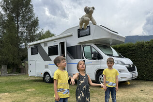 Drei kleine Kinder stehen vor ihrem Wohnmobil.