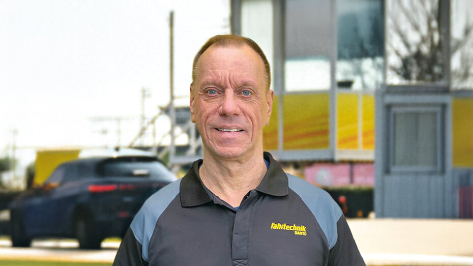 ÖAMTC Fahrtechnik-Instruktor. Er hat kurz geschorene Haare, blaue Augen und ist schon älter. Er trägt ein graues Oberteil und schaut in die Kamera.