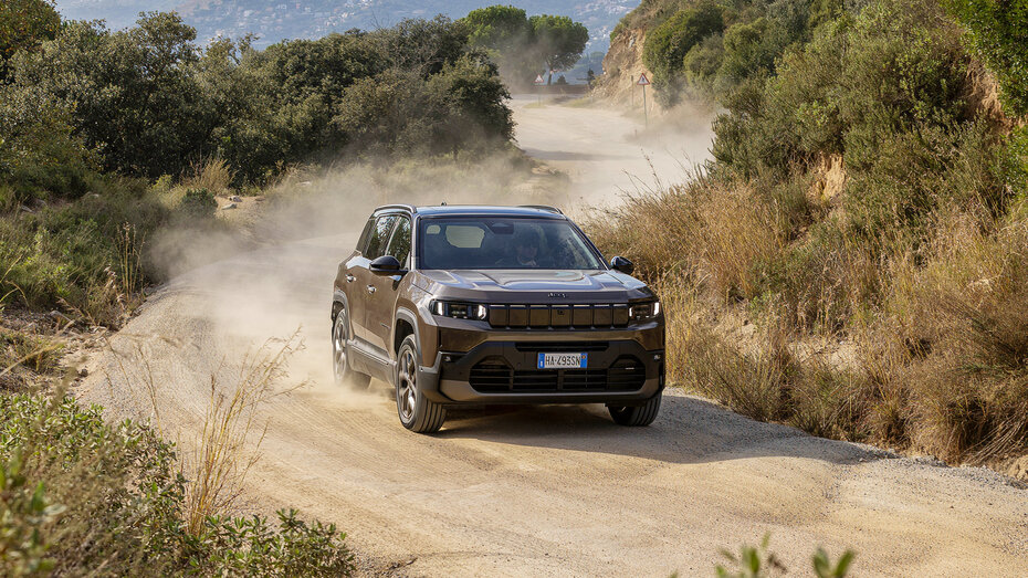 Ein grauer Jeep Compass fährt über eine unbefestigte Schotterstraße.