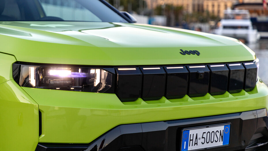 Front eines grünen Jeep mit schwarzem Kühlergrill und LED-Scheinwerfern. 