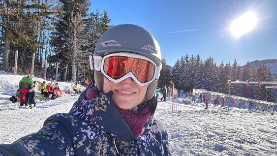 Selfie einer Frau mit Skihelm (hier die Redakteurin), im Hintergrund eine Skipiste am Kasberg.