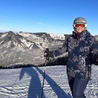 Frau im blau geblümten Skigewand steht vor dem Panorama des Karstgebirges im Salzkammergut.