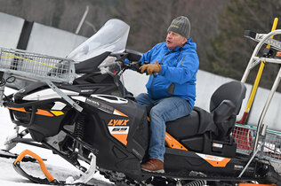 Ein Mann fährt auf eine Ski-Doo im Hintergrund Wälder.
