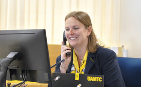 Reisebürokauffrau Katharina Wiesbauer am Telefon, wie sie auf den Computerbildschirm blickt.