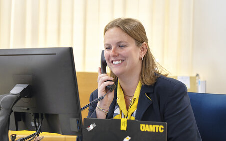 Reisebürokauffrau Katharina Wiesbauer am Telefon, wie sie auf den Computerbildschirm blickt.