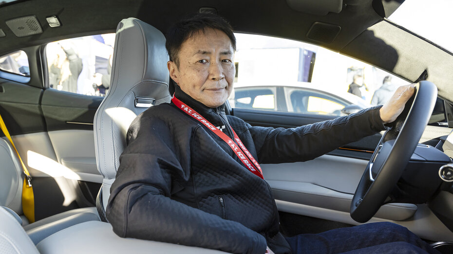 Kazunori Yamauchi im Auto am Steuer, er lächelt in die Kamera.