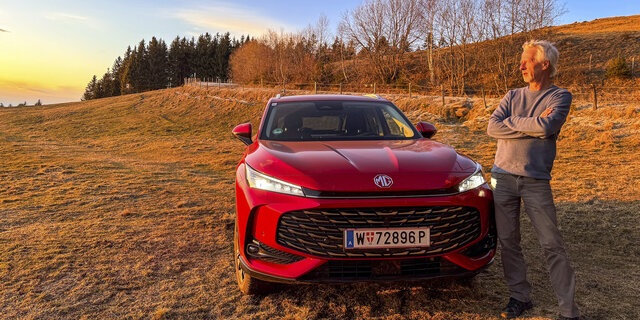 Bild zeigt einen auto-touring Redakteur bei Sonnenuntergang vor dem Testauto stehend.