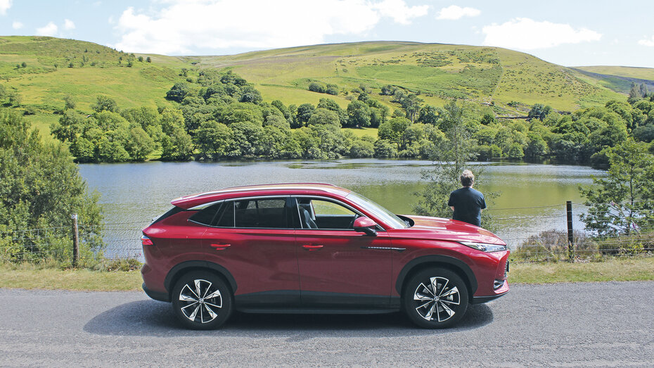 Redakteur steht in grüner walisischer Landschaft beim Test-Fahrzeug.