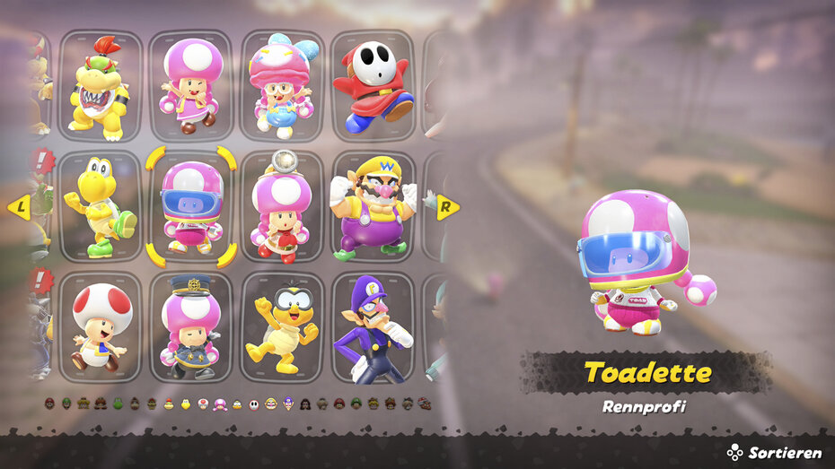Screenshot aus Mario Kart World. Man sieht das Charaktermenü, Toadette ist ausgewählt in ihrem Outfit "Rennfahrprofi"