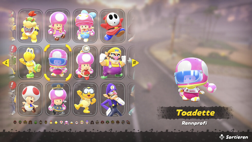 Screenshot aus Mario Kart World. Man sieht das Charaktermenü, Toadette ist ausgewählt in ihrem Outfit "Rennfahrprofi"