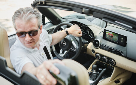 Eine Person fährt in einem Cabrio retour und blickt deshalb zurück.