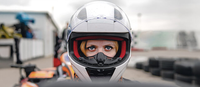 Frau mit weißem Sturzhelm im Cockpit